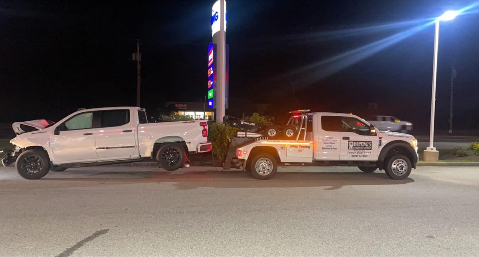 Whiting's wrecker towing a wrecked pickup at night